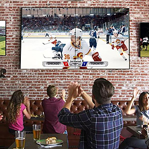 Patrons inside a restaurant cheering to a sports game on a large video wall installation
