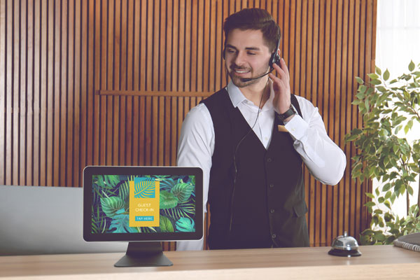 A hotel receptionist engaging with a countertop digital sign display