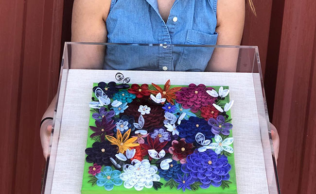 Woman holding a shadow box with hand-made paper flowers
