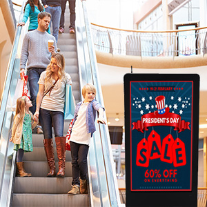 Shoppers in a mall looking at a digital floor sign advertising a sale
