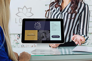 A hotel concierge explains how to use a countertop digital kiosk to a guest.