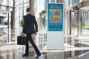 A businessman with briefcase scans a digital kiosk directory in an office lobby for wayfinding information.