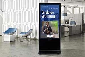 Floor-standing digital kiosk in a modern office lobby spotlighting an employee's contribution.