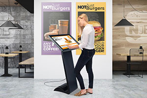 A woman interacts with a food menu on a touchscreen digital kiosk.