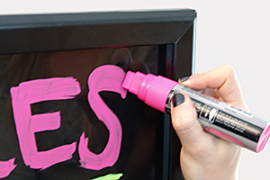 Closeup of a wet erase marker being used on a blackboard