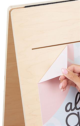 Hand peeling custom printed Phototex graphic from wooden A-frame