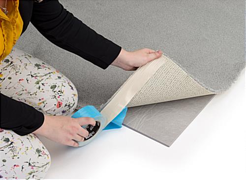 Padding and tape (sold separately) being shown securing carpet strips to the floor