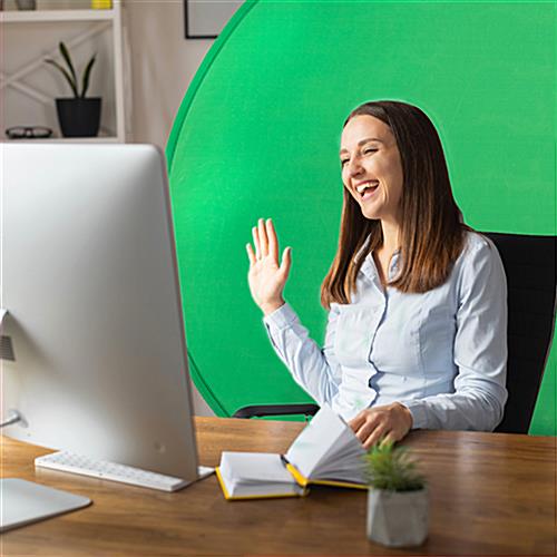 Woman sitting at desk with green screen background