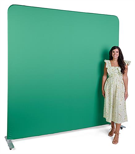 Angle from left of woman in front of green screen backdrop with aluminum feet on wheels