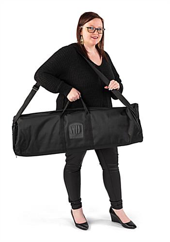 Woman carrying the 33"W premium retractable banner stand in the included tote bag