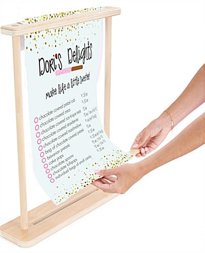 Inserting dowel into bottom of custom banner insert that sits in wooden frame of tabletop banner